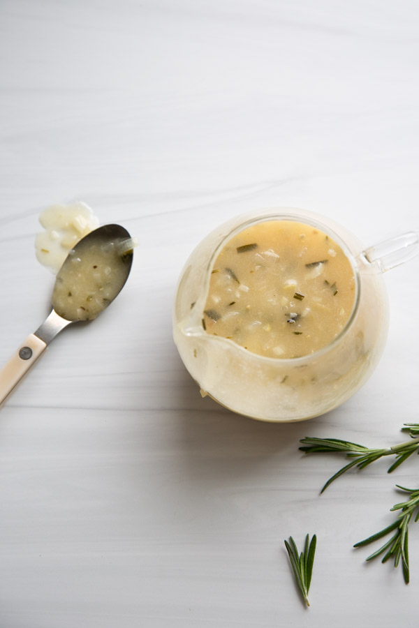 gluten-free gravy in a bowl on a marble board with spoon