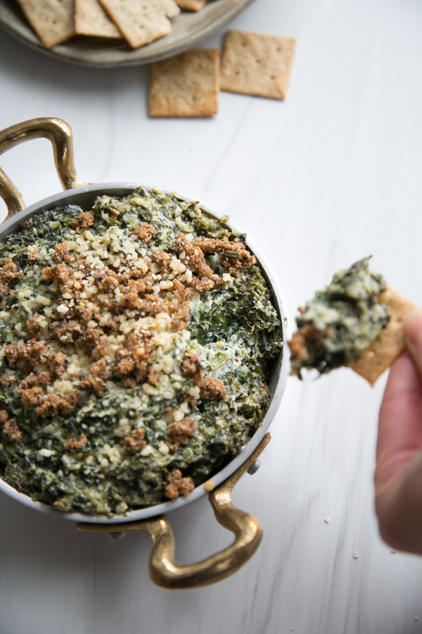 dairy-free spinach dip with gluten-free crackers dipping into it