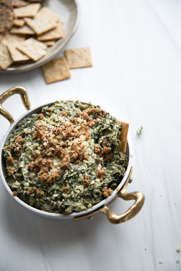 baked dairy-free spinach dip with gluten-free cracker in the skillet
