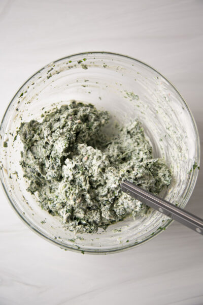 A bowl of spinach dip mixed together