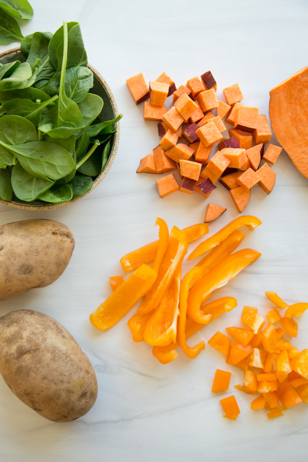 low fodmap hash ingredients on a counter: spinach, sweet potato, regular potato, bell pepper