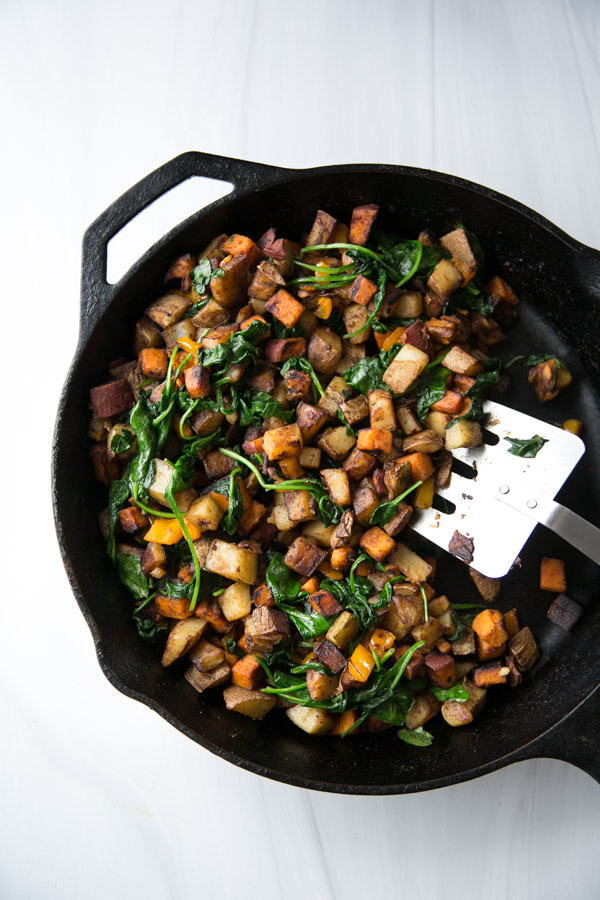 skillet with gluten-free low fodmap breakfast hash with wilted spinach and spatula