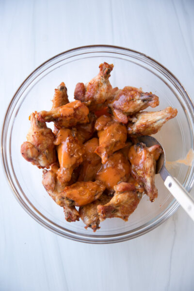 Gluten-free chicken wings served in a bowl and topped with dairy-free buffalo sauce
