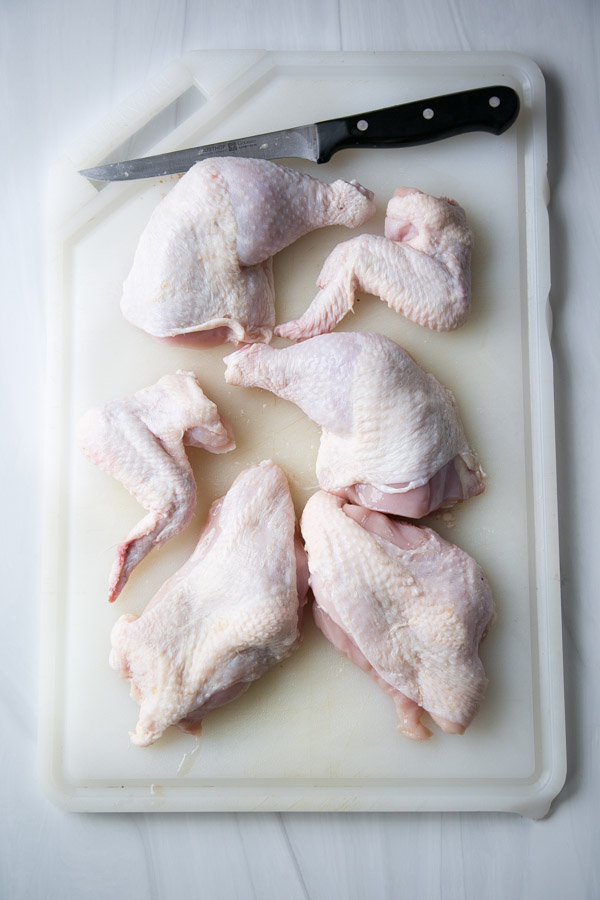 whole chicken cut into pieces on a cutting board