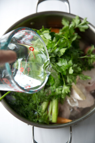 pouring water or chicken and vegetables in a pot