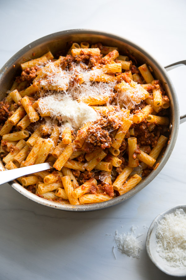 low fodmap pasta bolognese with ground turkey garnished with parmesan in a skillet