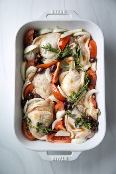 provencal chicken in a casserole with tomatoes and onions around it