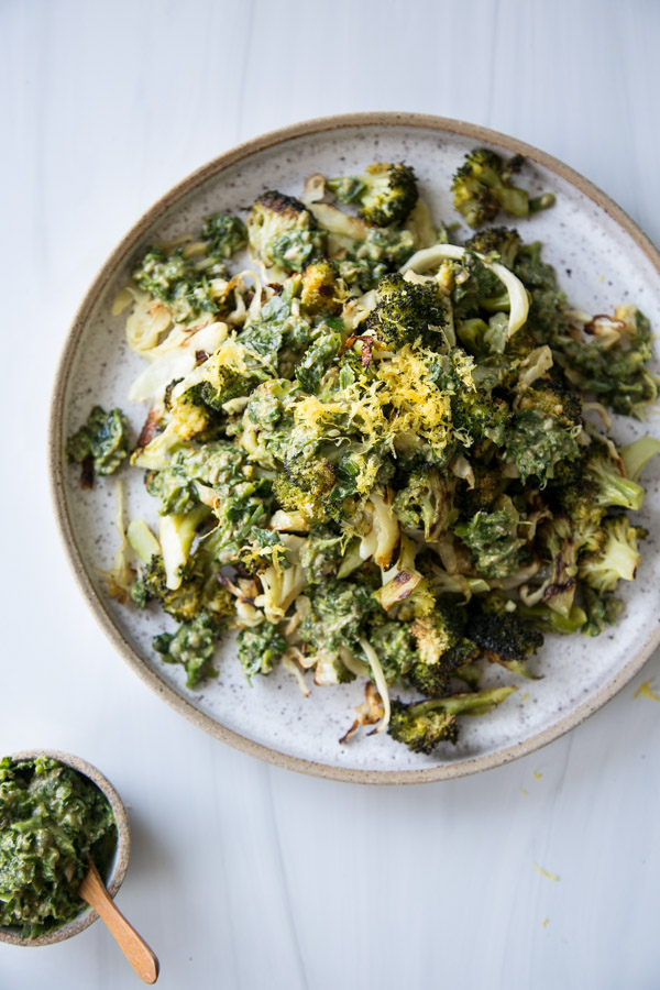 low fodmap roasted broccoli and cabbage on a platter with lemon zest and caper pesto