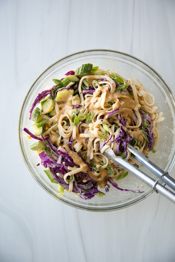 Use tongs to transfer cold sesame noodle salad and Asian dressing to mixing bowl